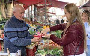 Women and vendor at the market tasting fruit